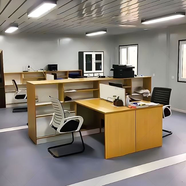 It's a prefabricated house with an office layout with yellow desks and chairs and bookcases